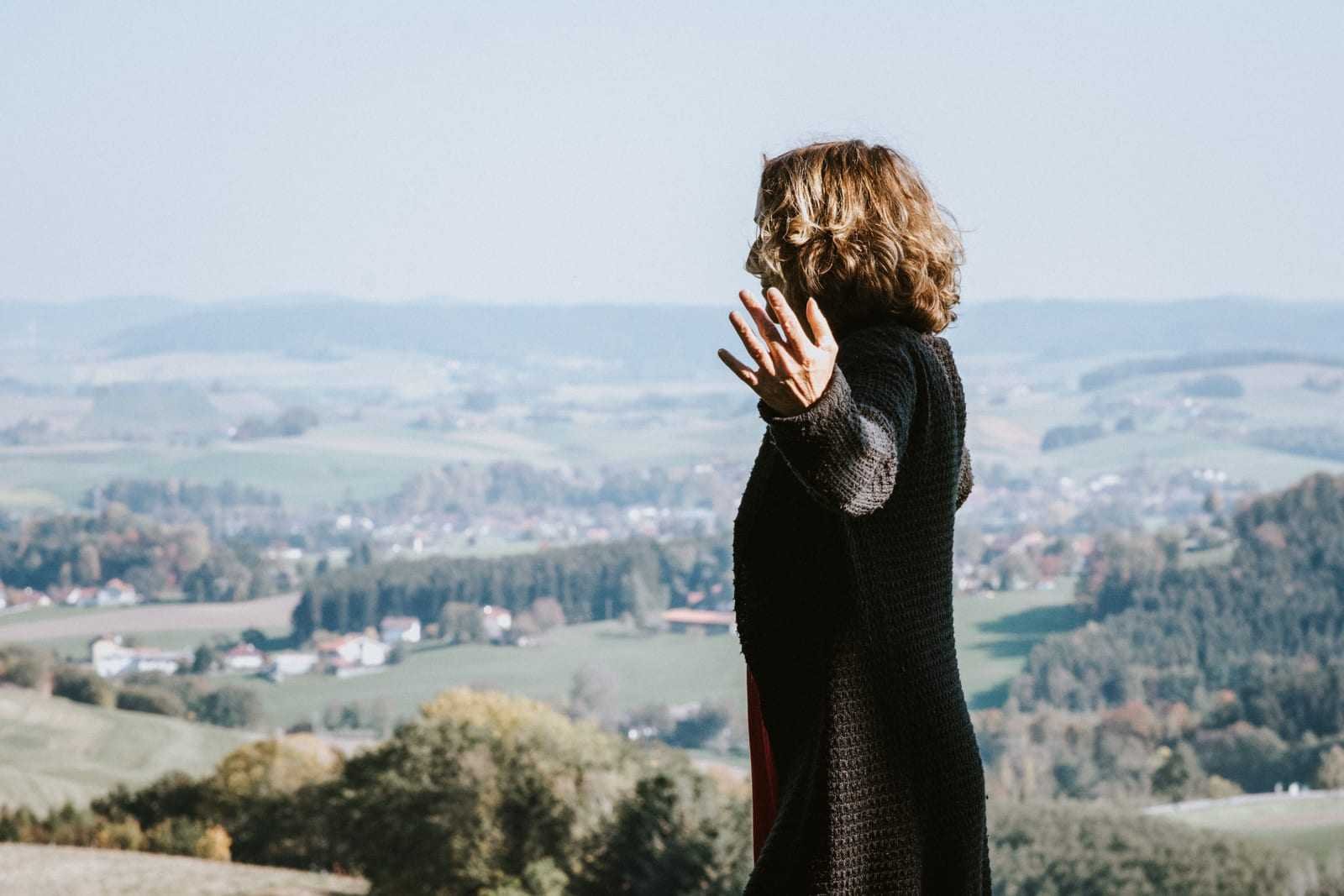 Eine erhobene Hand vor weiter Landschaft, die Energie des Ortes