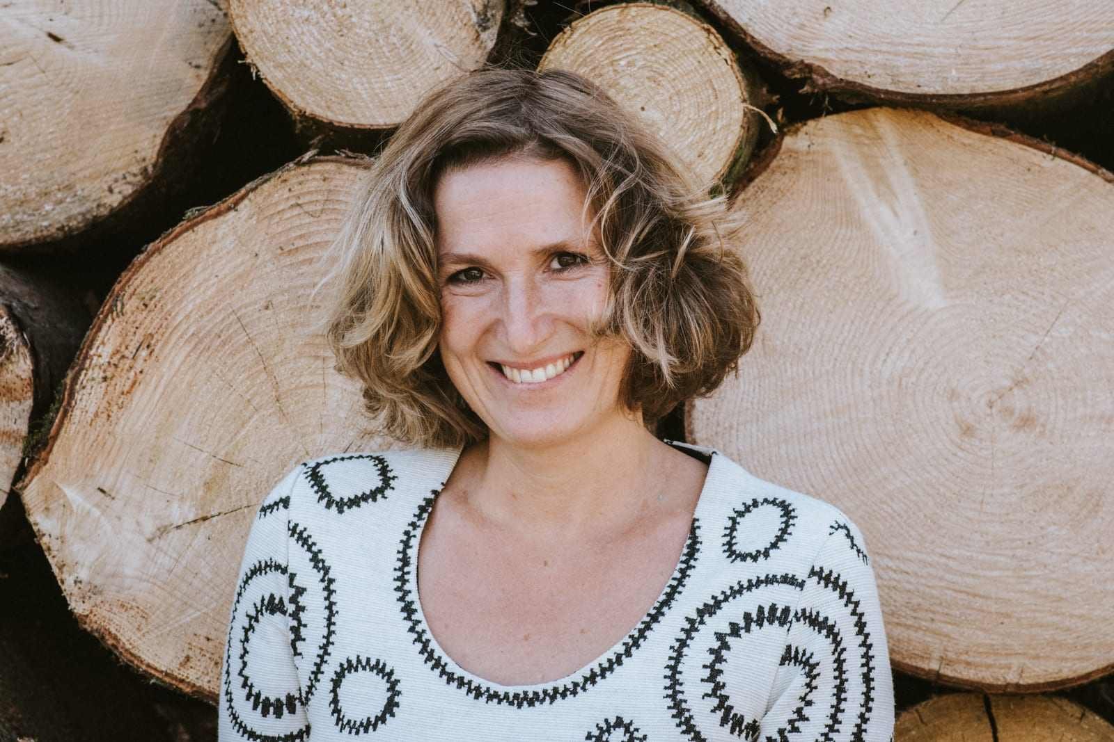 Claudia Reisecker neben gestapeltem Holz, herbstlich gekleidet